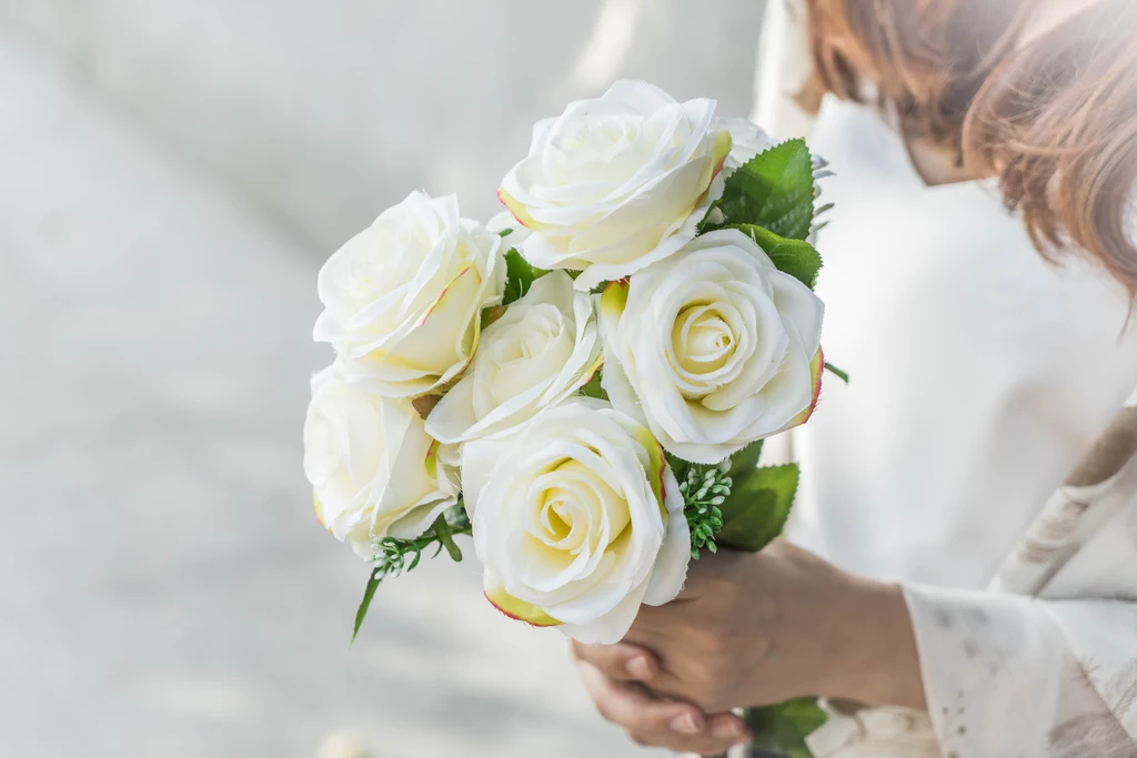 Białe róże symbolizują czystość i niewinność, dlatego często są wybierane do bukietów ślubnych.