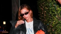 Hailey Bieber zaprezentowała się na kolacji w białym t-shircie, krótkich spodenkach i sportowych butach. Dopełnieniem stylizacji były czarne okulary przeciwsłoneczne i pomarańczowa torebka. Główną rolę grała jednak kurtka. 