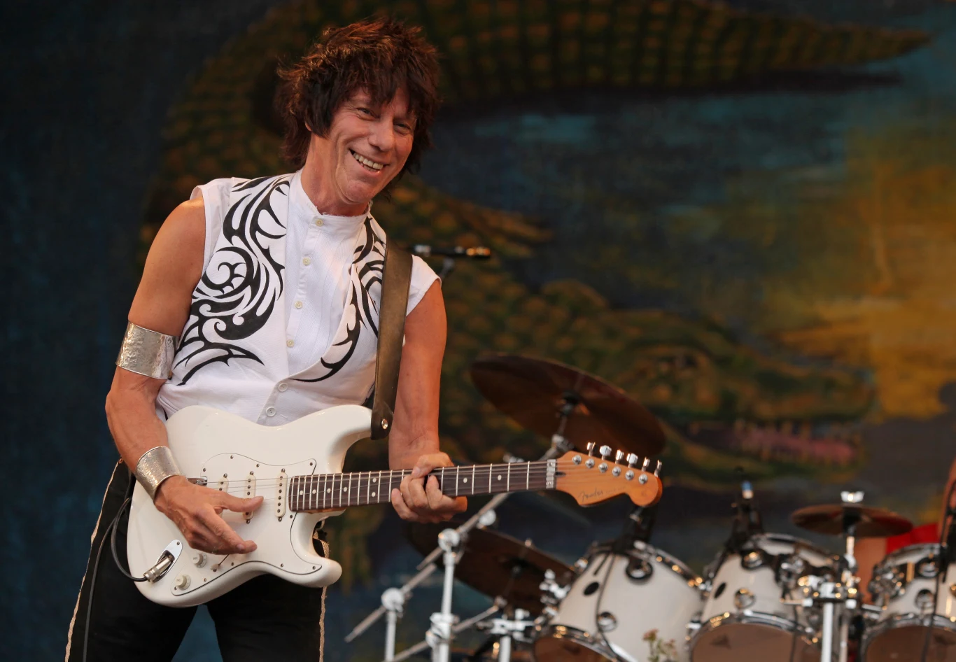 Jeff Beck (1944-2023). Brytyjski muzyk reprezentujący gatunki rocka, hard rocka, heavy metalu, jazz rocka, blues rocka. Wychowywał się w muzycznej rodzinie. Jego mama grała na pianinie, a cała rodzina była zafascynowana muzyką co wpłynęło na młodego Jeffa. Jeff Beck nauczył się grać na gitarze i zaczął występować w Londynie. Pracował jako muzyk sesyjny z Screaming Lord Sutch i the Tridents. W 1965 r. zastąpił Erica Claptona w Yardbirds. W 1967 r. utworzył własny zespół - Jeff Beck Group w składzie z Rodem Stewartem jako wokalistą i Ronem Woodem (późniejszym gitarzystą The Rolling Stones) na basie. Razem wydali dwa albumy - "Truth" (1968) oraz "Beck-Ola" (1969) - będące w kolejnych latach punktem odniesienia dla nowo powstałych zespołów rockowych. Na początku lat 70. Jeff Beck, już ze zmienionym składem zespołu, nagrał kolejne dwa albumy - "Rough and Ready" oraz "The Jeff Beck Group". W 1973 r. z nowym zespołem gitarzysta nagrał album "Beck, Bogert and Appice". Odchodząc od hard rocka Beck nagrał "Blow By Blow" (1975) and "Wired" (1976). By promować album "Jeff", Beck wyruszył w 2003 r. w trasę z legendą bluesa B.B. Kingiem podczas 12. dorocznego B.B. King Music Festival. W kolejnych latach odbył wiele tournee: po Australii i Nowej Zelandii, Japonii, Europie i Kanadzie. W połowie 2022 r. wydał wspólny album z aktorem Johnnym Deppem, który jest też gitarzystą w rockowej supergrupie The Hollywood Vampires. Jeff Beck zagrał też gościnnie na ostatniej płycie Ozzy'ego Osbourne'a - "Patient Number 9" z czerwca 2022 r. Współpracował z takimi artystami jak: Eric Clapton, Rod Stewart, Tina Turner, Mick Jagger, Jon Bon Jovi, Roger Waters, Stevie Wonder czy ZZ Top. Zmarł 10 stycznia 2023 roku w Nowym Jorku. Miał 78 lat. Jeff Beck (1944-2023). Brytyjski muzyk reprezentujący gatunki rocka, hard rocka, heavy metalu, jazz rocka, blues rocka. Wychowywał się w muzycznej rodzinie. Jego mama grała na pianinie, a cała rodzina była zafascynowana muzyką co wpłynęło na młodego Jeffa. Jeff Beck nauczył się grać na gitarze i zaczął występować w Londynie. Pracował jako muzyk sesyjny z Screaming Lord Sutch i the Tridents. W 1965 r. zastąpił Erica Claptona w Yardbirds. W 1967 r. utworzył własny zespół - Jeff Beck Group w składzie z Rodem Stewartem jako wokalistą i Ronem Woodem (późniejszym gitarzystą The Rolling Stones) na basie. Razem wydali dwa albumy - "Truth" (1968) oraz "Beck-Ola" (1969) - będące w kolejnych latach punktem odniesienia dla nowo powstałych zespołów rockowych. Na początku lat 70. Jeff Beck, już ze zmienionym składem zespołu, nagrał kolejne dwa albumy - "Rough and Ready" oraz "The Jeff Beck Group". W 1973 r. z nowym zespołem gitarzysta nagrał album "Beck, Bogert and Appice". Odchodząc od hard rocka Beck nagrał "Blow By Blow" (1975) and "Wired" (1976). By promować album "Jeff", Beck wyruszył w 2003 r. w trasę z legendą bluesa B.B. Kingiem podczas 12. dorocznego B.B. King Music Festival. W kolejnych latach odbył wiele tournee: po Australii i Nowej Zelandii, Japonii, Europie i Kanadzie. W połowie 2022 r. wydał wspólny album z aktorem Johnnym Deppem, który jest też gitarzystą w rockowej supergrupie The Hollywood Vampires. Jeff Beck zagrał też gościnnie na ostatniej płycie Ozzy'ego Osbourne'a - "Patient Number 9" z czerwca 2022 r. Współpracował z takimi artystami jak: Eric Clapton, Rod Stewart, Tina Turner, Mick Jagger, Jon Bon Jovi, Roger Waters, Stevie Wonder czy ZZ Top. Zmarł 10 stycznia 2023 roku w Nowym Jorku. Miał 78 lat.