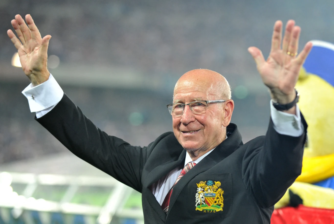 Sir Robert Charlton (1937-2023). Legenda angielskiego futbolu, były piłkarz m.in. Manchesteru United, w którym spędził większość kariery. 106-krotny reprezentant Anglii. W swoim CV ma mnóstwo sukcesów. Był jednym z najważniejszych członków drużyny, która w 1966 roku zdobyła tytuł mistrza świata. W tym samym roku Sir Bobby Charlton został laureatem prestiżowej nagrody indywidualnej dla zawodnika - Złotej Piłki. Sir Bobby Chartlon łącznie rozegrał aż 606 meczów w trykocie Manchesteru United. Dla "Czerwonych Diabłów" grał przez 17 lat, zdobywając między innymi trzy mistrzostwa Anglii. Był jednym ze szczęśliwców, którzy przeżyli katastrofę lotniczą z 1958 roku. Samolot z piłkarzami "Czerwonych Diabłów" na pokładzie rozbił się wówczas podczas próby startu. Śmierć poniosły 23 osoby, w tym ośmiu zawodników. W 1994 królowa Elżbieta II nadała mu tytuł szlachecki. Bobby Charlton zmarł 21 października 2023 roku. Miał 86 lat. Sir Robert Charlton (1937-2023). Legenda angielskiego futbolu, były piłkarz m.in. Manchesteru United, w którym spędził większość kariery. 106-krotny reprezentant Anglii. W swoim CV ma mnóstwo sukcesów. Był jednym z najważniejszych członków drużyny, która w 1966 roku zdobyła tytuł mistrza świata. W tym samym roku Sir Bobby Charlton został laureatem prestiżowej nagrody indywidualnej dla zawodnika - Złotej Piłki. Sir Bobby Chartlon łącznie rozegrał aż 606 meczów w trykocie Manchesteru United. Dla "Czerwonych Diabłów" grał przez 17 lat, zdobywając między innymi trzy mistrzostwa Anglii. Był jednym ze szczęśliwców, którzy przeżyli katastrofę lotniczą z 1958 roku. Samolot z piłkarzami "Czerwonych Diabłów" na pokładzie rozbił się wówczas podczas próby startu. Śmierć poniosły 23 osoby, w tym ośmiu zawodników. W 1994 królowa Elżbieta II nadała mu tytuł szlachecki. Bobby Charlton zmarł 21 października 2023 roku. Miał 86 lat.
