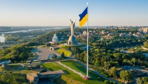 Pomnik Matki Ojczyzny w Kijowie na tle ukraińskiej flagi.