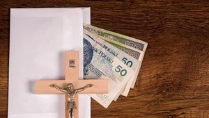 Kolęda 2024. Koperta wraz z pieniędzmi i krucyfiks leżący na niej.