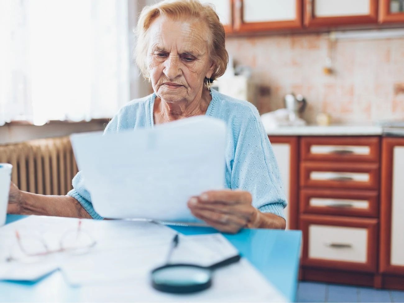 Jeśli seniorka otrzymywała przez 25 lat najniższą krajową pensję, to jej świadczenie wyniesie prawdopodobnie 1978,49 zł brutto Seniorka siedzi przy kuchennym stole, na którym ma rozłożone rachunki