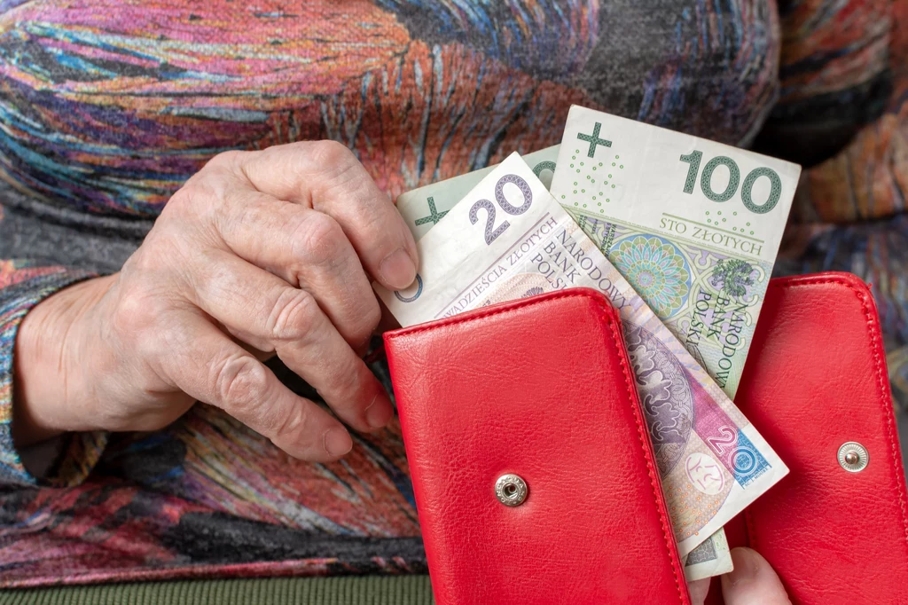 Starsza kobieta trzyma banknoty w ręce, które wyciąga z portfela Starsza kobieta trzyma banknoty w ręce, które wyciąga z portfela