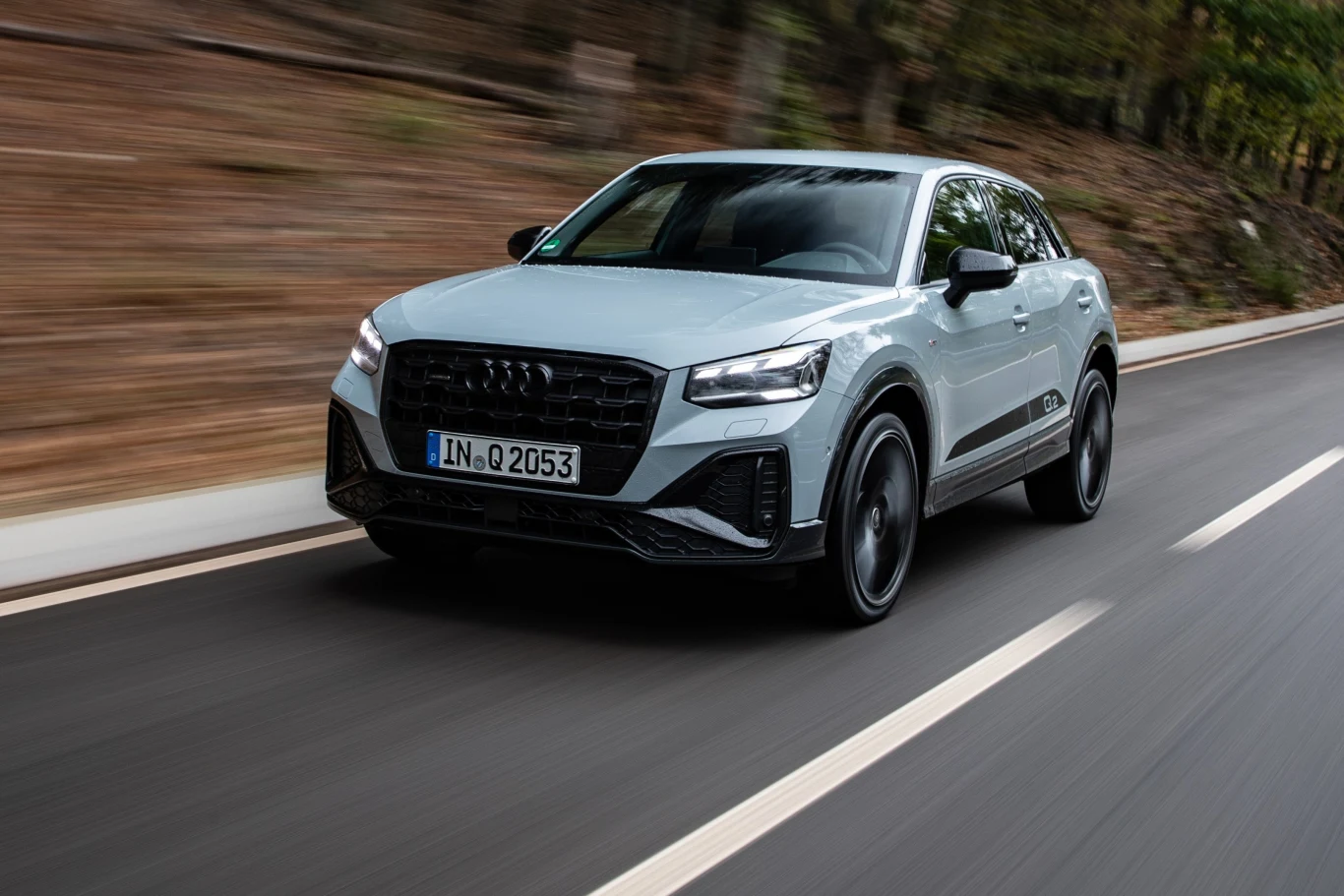 Używane Audi Q2 – wady, zalety i koszty eksploatacji. Srebrne Audi Q2 w ruchu na leśnej drodze, otoczone rozmytym tłem drzew.