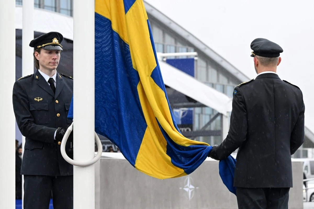 Ceremonia wciągnięcia flagi Szwecji na masz przed kwaterą główną NATO 