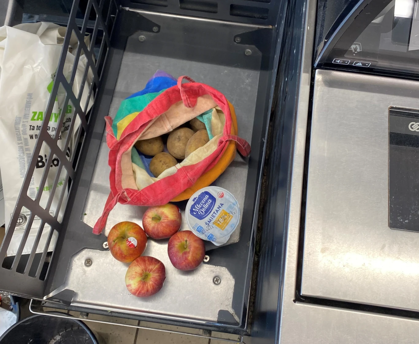 Zakupy w strefie pakowania kasy samoobsługowej. Widać ziemniaki zapakowane w materiałowej torbie.