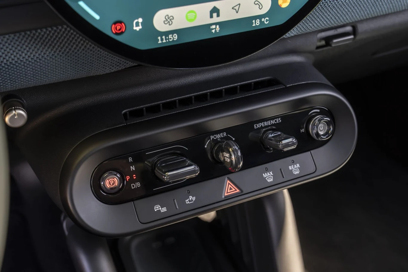 Pod okrągłym wyświetlaczem znajduje się z panel z fizycznymi przełącznikami i dźwigniami. Z jego poziomu możemy włączyć auto lub obsługiwać skrzynię biegów.