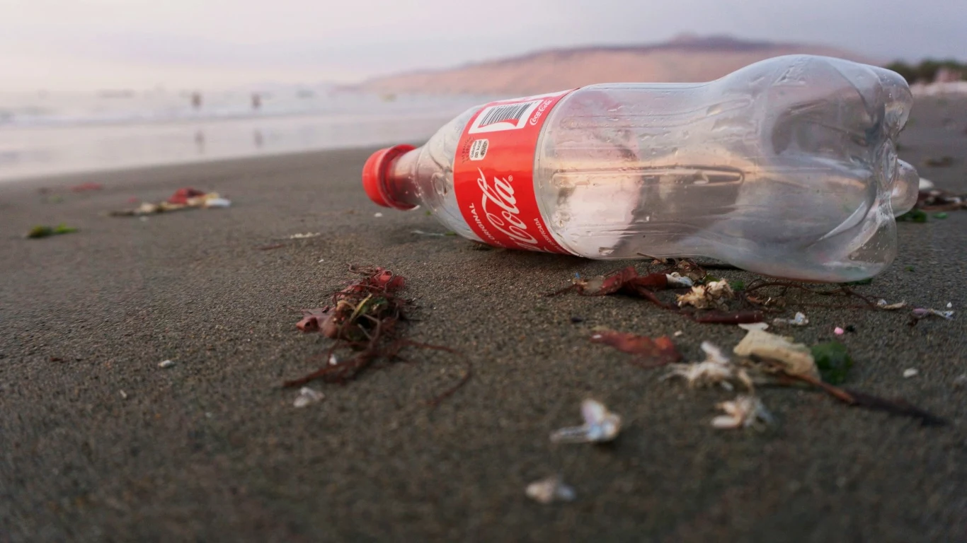 Pusta butelka Coca-Coli na plaży