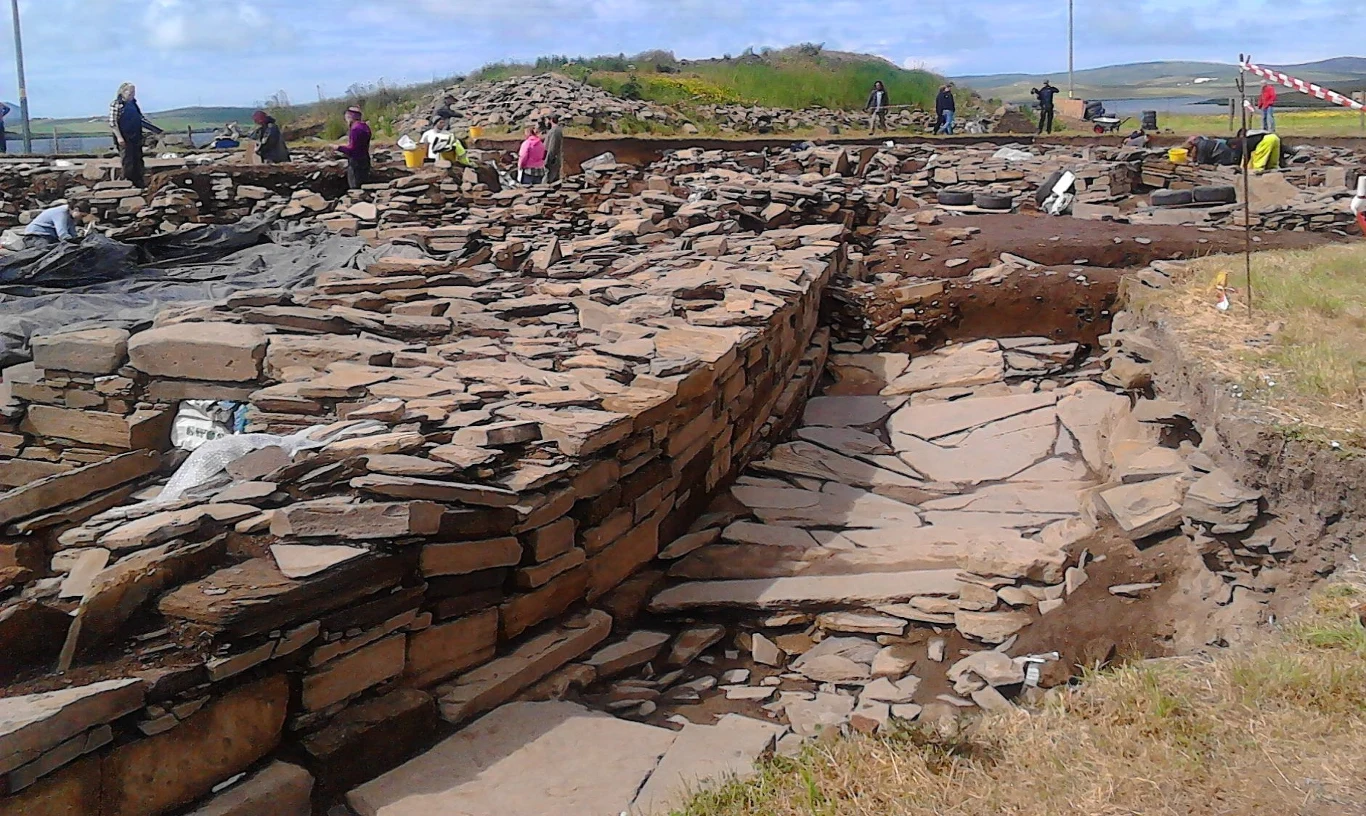 Szkocja skrywa wiele tajemnic. Naukowcy rozwiązali jedną z nich (zdj. ilustracyjne) Ruiny kamiennej budowli na tle zielonego krajobrazu, kilku archeologów pracuje przy wykopaliskach.