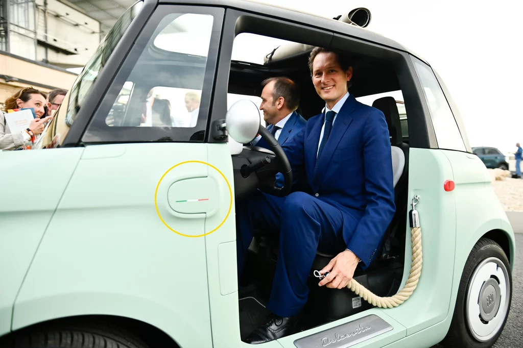 Prezes Fiata John Elkann podczas prezentacji Fiata Topolino w 2023 roku. Na błotniku dostrzeżemy niewielką włoską flagę