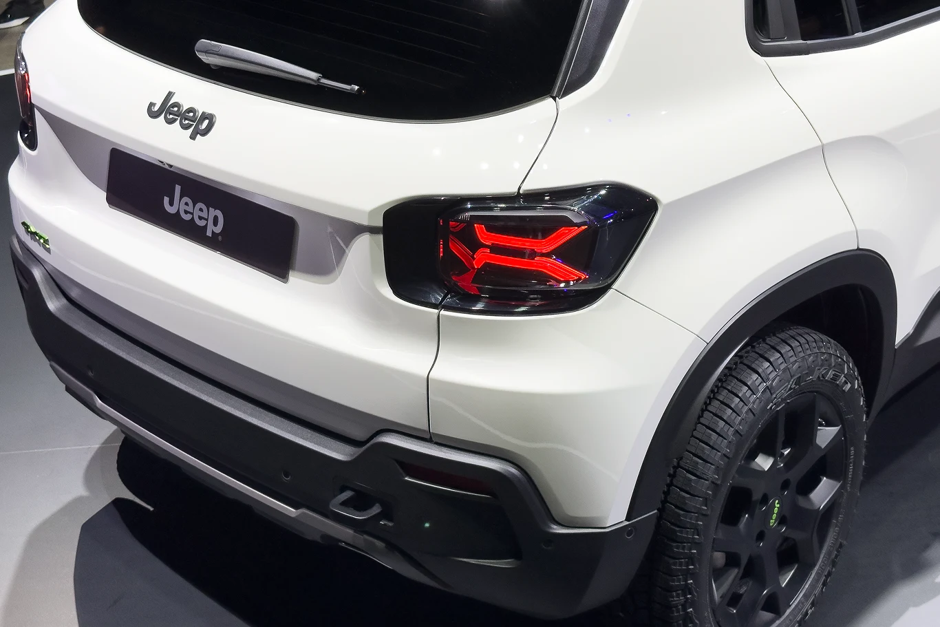 Jeep chce ponownie liczyć się na europejskim rynku samochodów. Pomogą mu Chińczycy. Tylny widok białego Jeepa z nowoczesnymi światłami na błyszczącej, ciemnej nawierzchni.