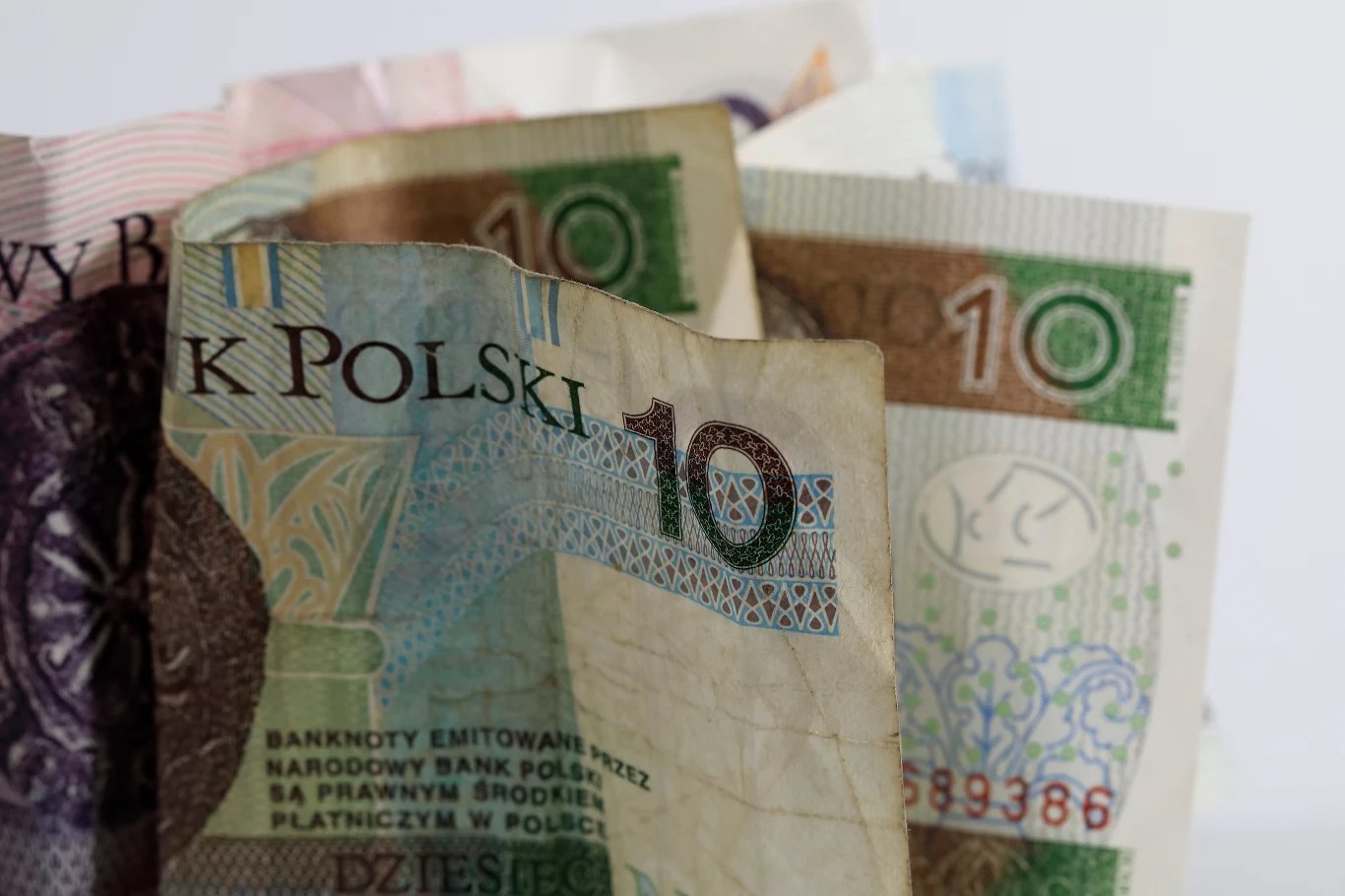 Uszkodzone banknoty - jak odzyskać pieniądze? Polskie banknoty różnych nominałów pionowo ułożone, widoczne kolory i napis 'BANK POLSKI'.