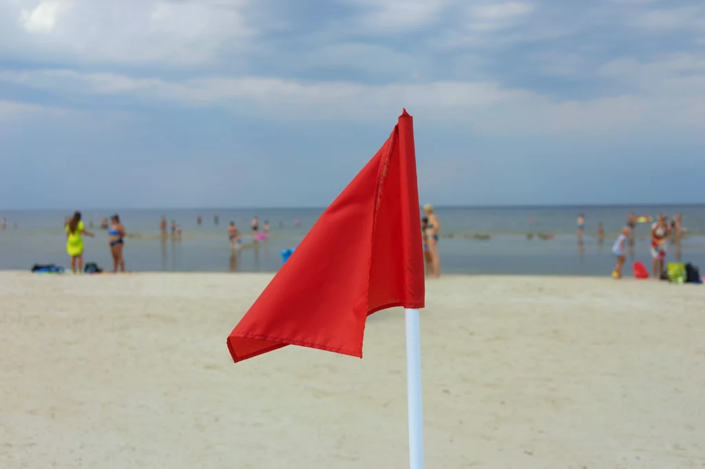 Na plaży powinniśmy zwrócić uwagę na kolor flagi. Czerwona to zakaz kąpieli.