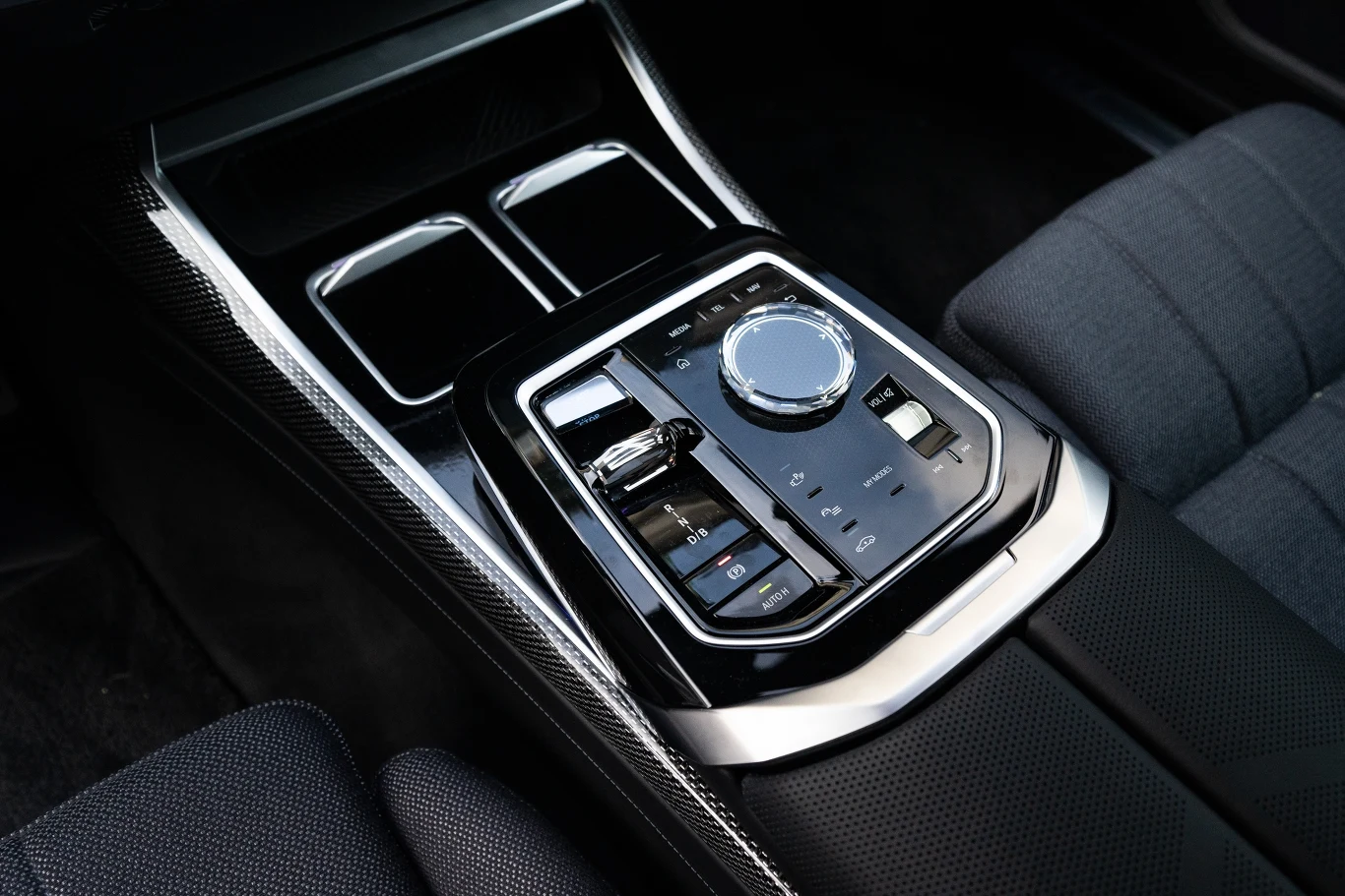 W tunelu środkowym znajdziemy miejsce na naładowanie smarftona, dwa miejsca na napoje i panel z fizycznym pokrętłem iDrive.