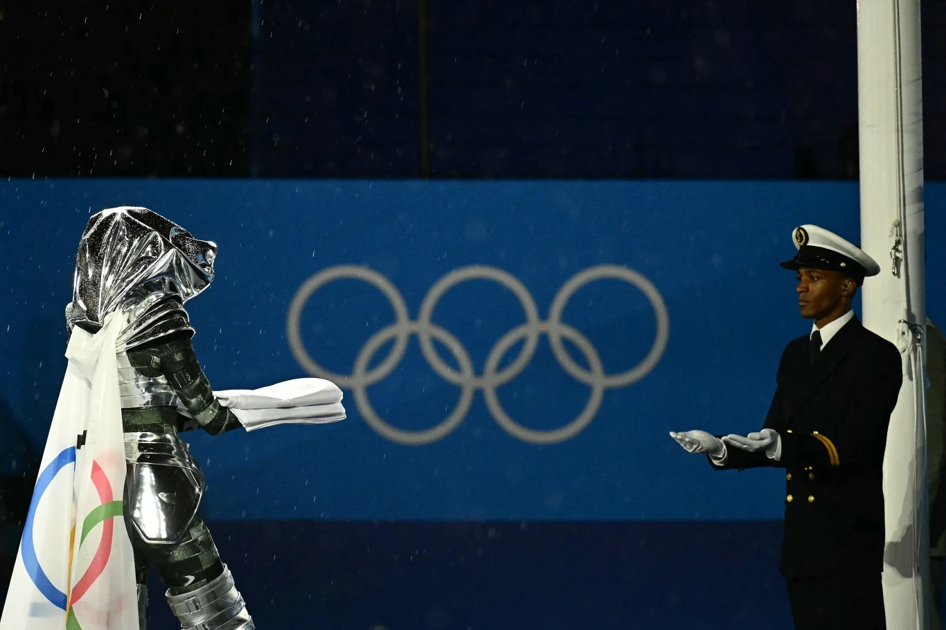 Moment przekazania flagi olimpijskiej przed zawieszeniem jej na maszcie Moment przekazania flagi olimpijskiej przed zawieszeniem jej na maszcie