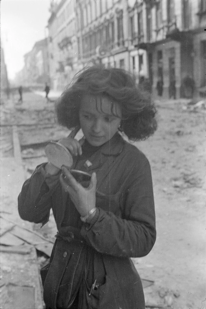 Dziewczyna z lusterkiem po bombardowaniu na ul. Złotej przy skrzyżowaniu z ul. Zgoda, połowa września 1944 r. (fot. Eugeniusz Lokajski „Brok”)