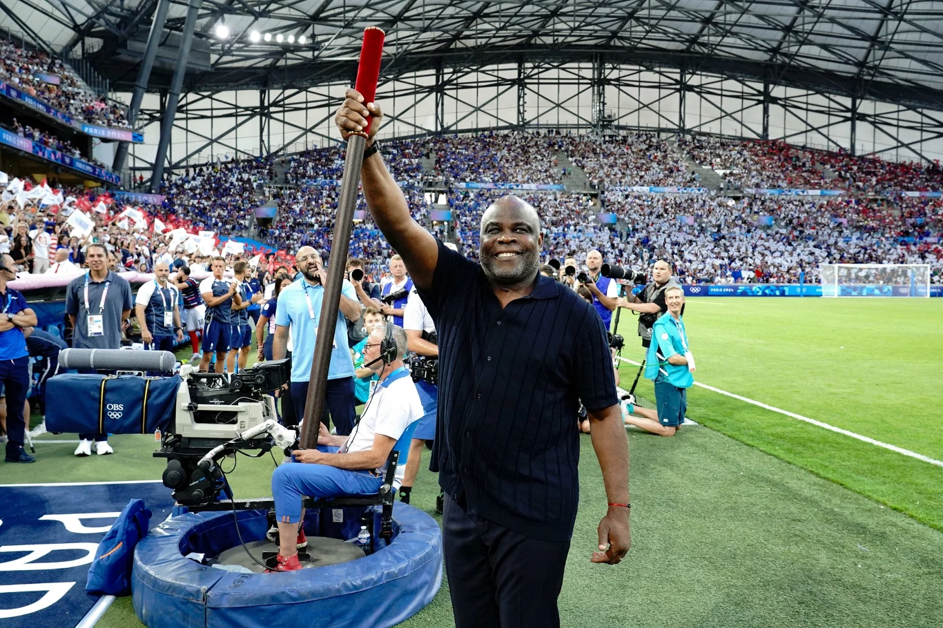 Basile Boli z drewnianym kijem, który otwierał rywalizację na igrzyskach Basile Boli z drewnianym kijem, który otwierał rywalizację na igrzyskach