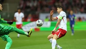 Bramkarz Dominik Livaković atakuje piłkę i Roberta lewandowskiego
