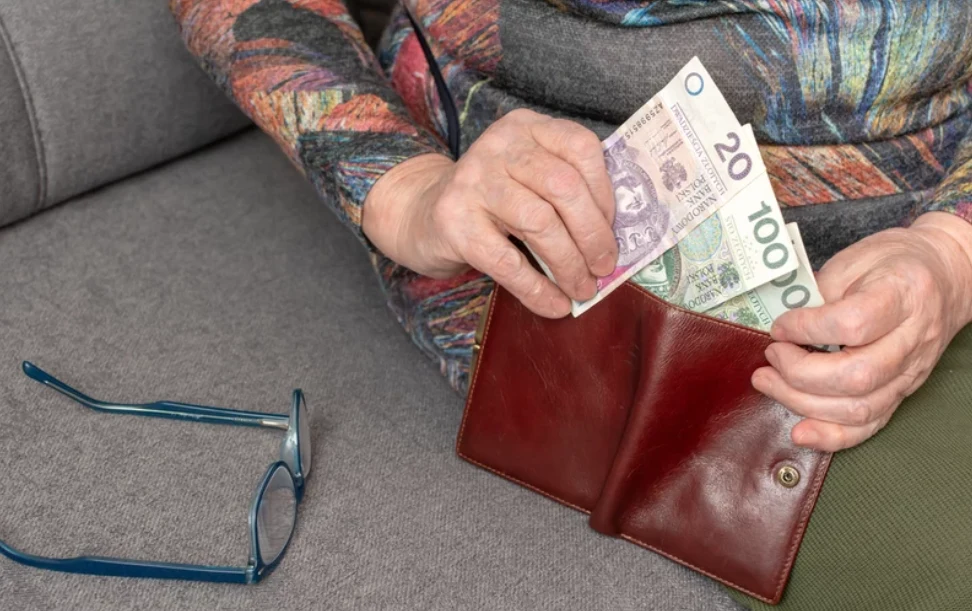 Nawet 150 tys. seniorów pobiera zaniżone emerytury Starsza pani wyciąga z portfela pieniądze o nominałach 20 zł i 100 zł