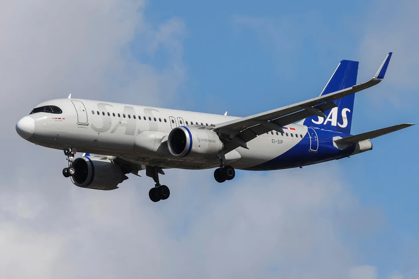 Scandinavian Airlines (SAS) odwołuje loty. W kwietniu - tysiąc. Za decyzją stoją rosnące ceny paliwa lotniczego Samolot Scandinavian Airlines (SAS) w locie. Na zdjęciu bok maszyny z wysuniętym podwoziem. Tłem nieco zachmurzone niebo.