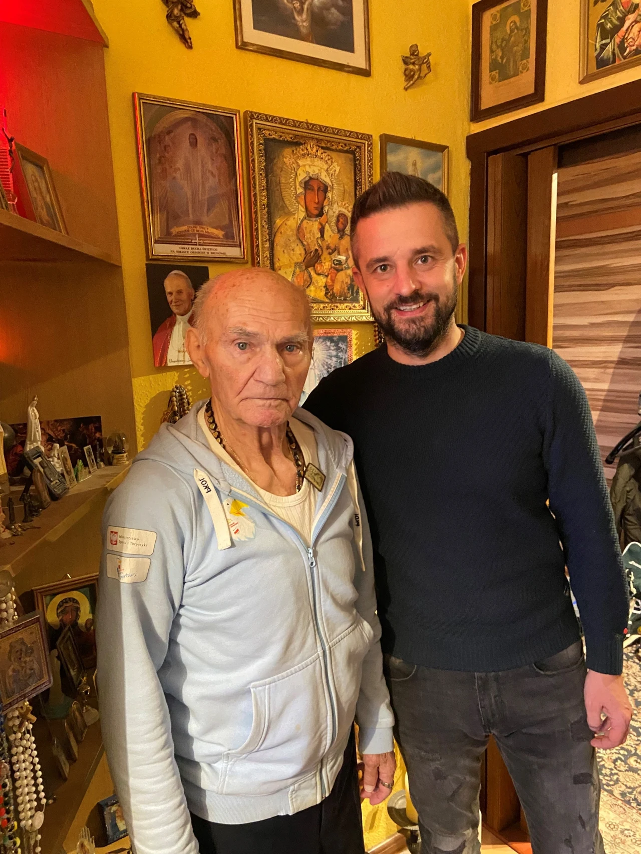 Autor reportażu razem z panem Marianem w drugim pokoiku, gdzie mistrz ma mnóstwo różańców, a także między innymi duży obraz ze swoją podobizną z młodych lat