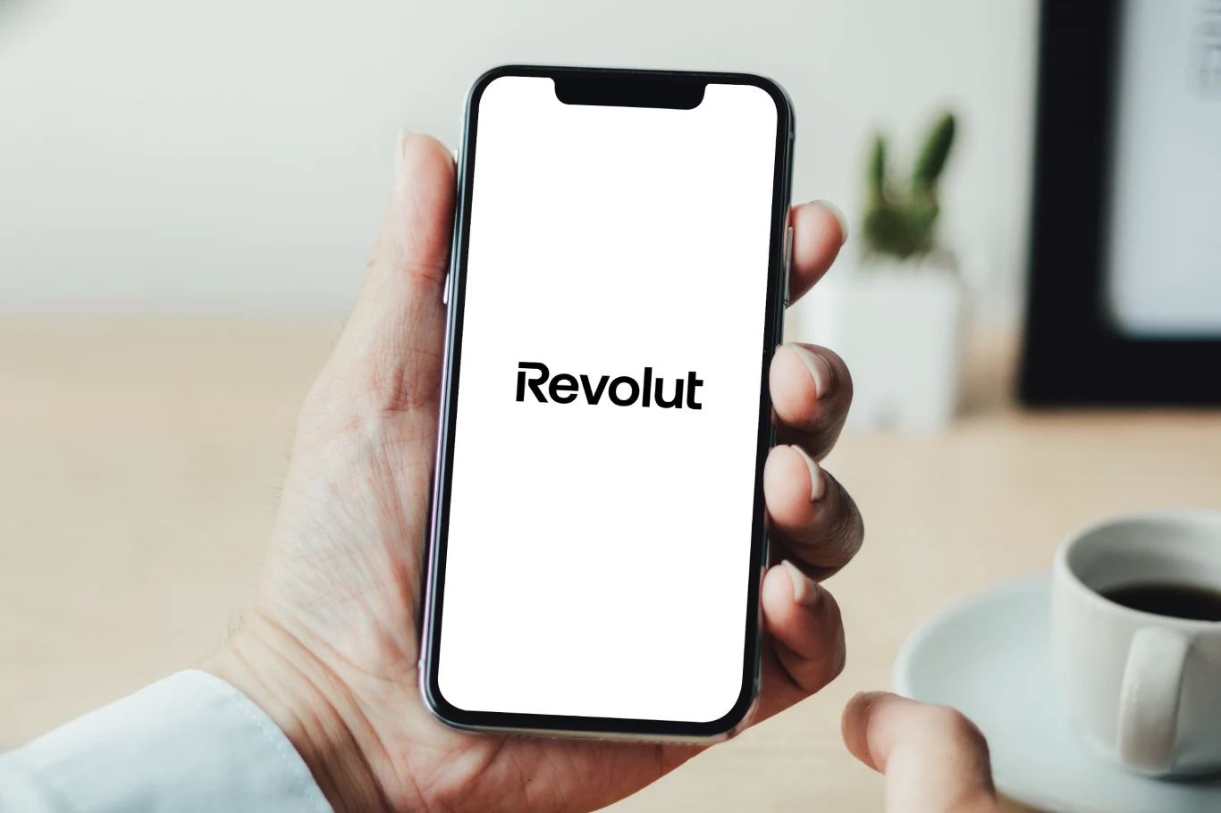 Revolut z nowymi funkcjami w aplikacji. Aplikacja Revolut w telefonie. Smartfon trzymany w dłoni.