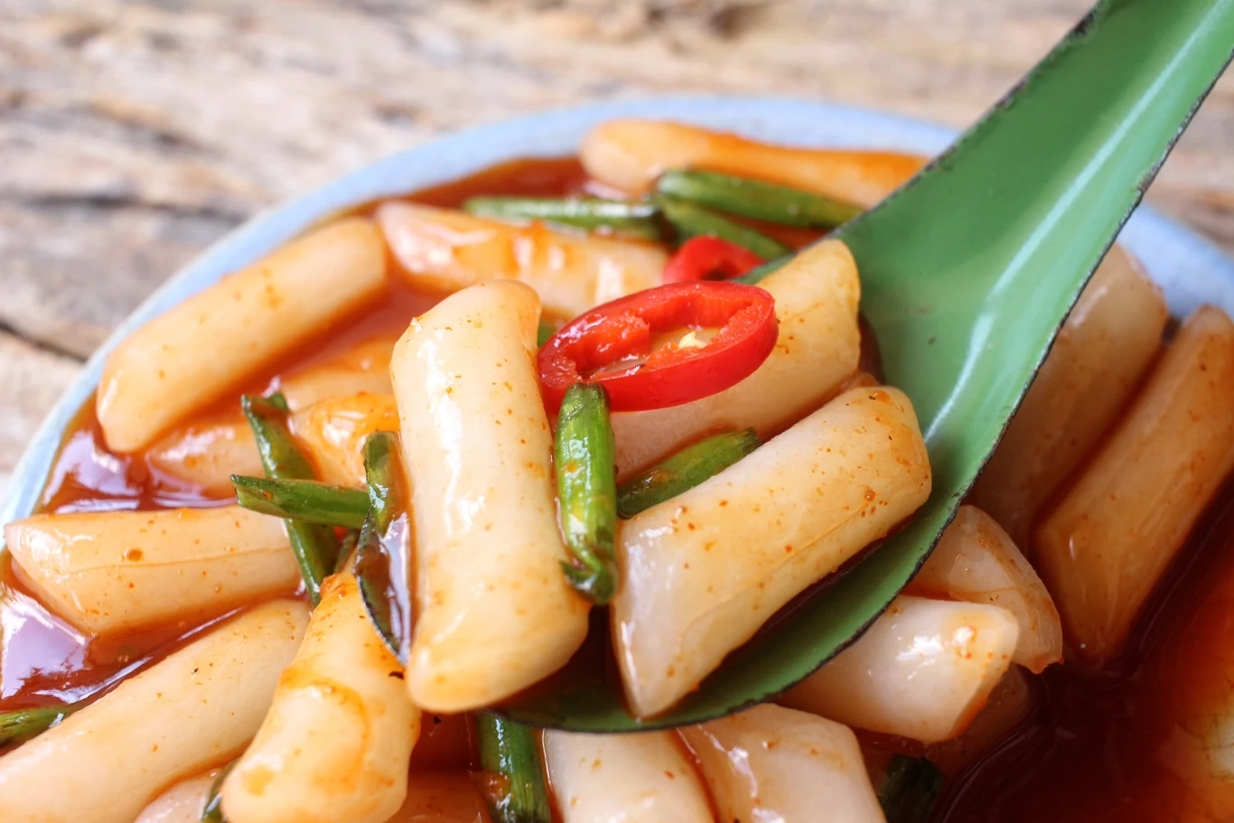 Ttekbokki podaje się z ostrym sosem, papryczkami chili i zieloną cebulką Ttekbokki podaje się z ostrym sosem, papryczkami chili i zieloną cebulką