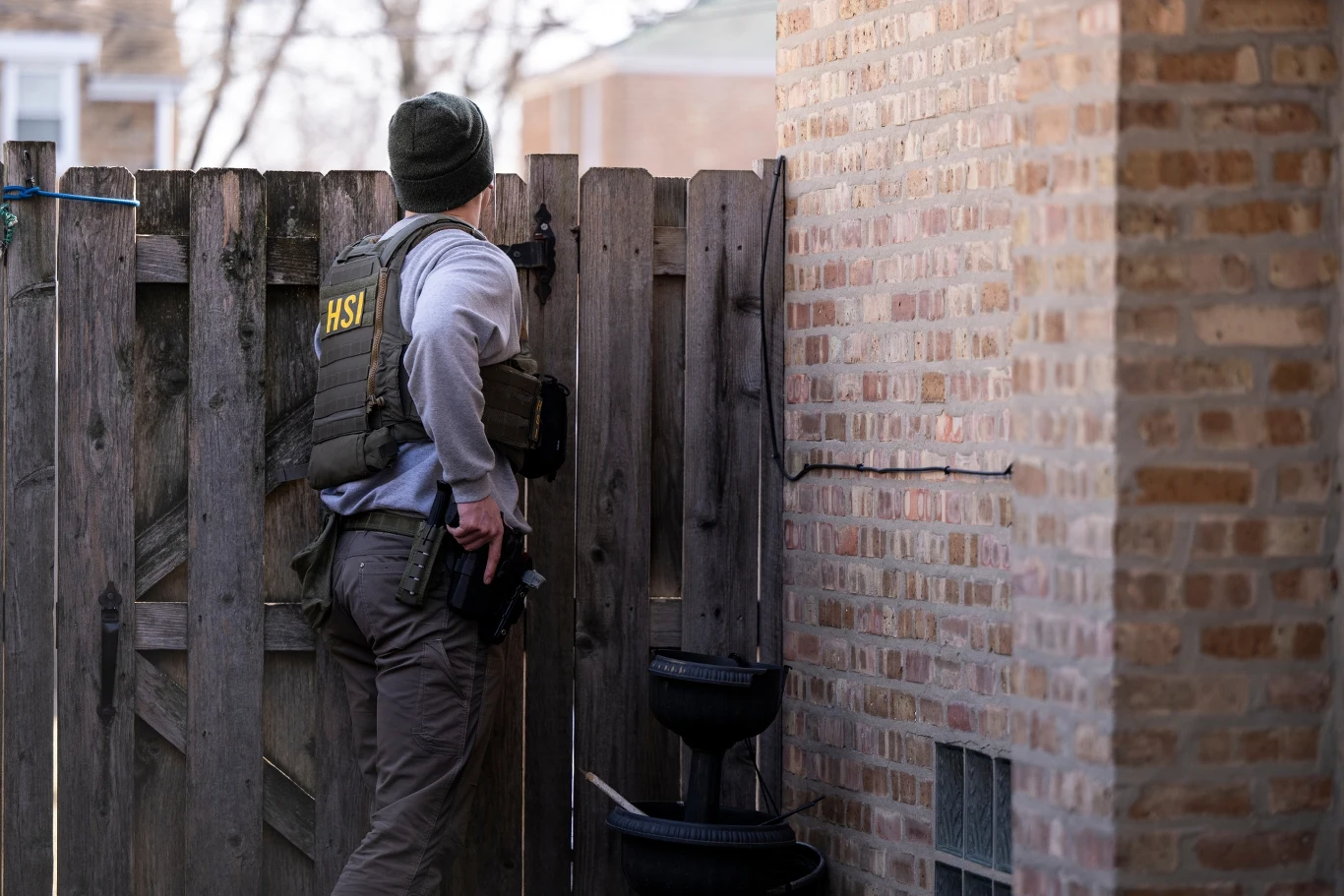 Agent Homeland Security Investigations zagląda do budynku mieszkalnego