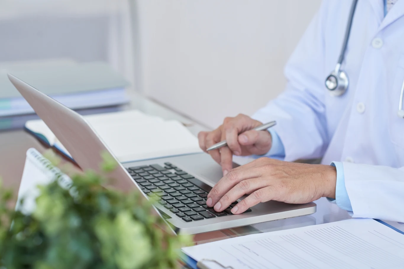 Jednodniowe L4 mogą służyć wydłużaniu weekendów. Jest problem ze skutecznym kontrolowaniem pracowników. Lekarz w białym kitlu wpisuje dane na laptopie, obok na biurku formularze i długopis.