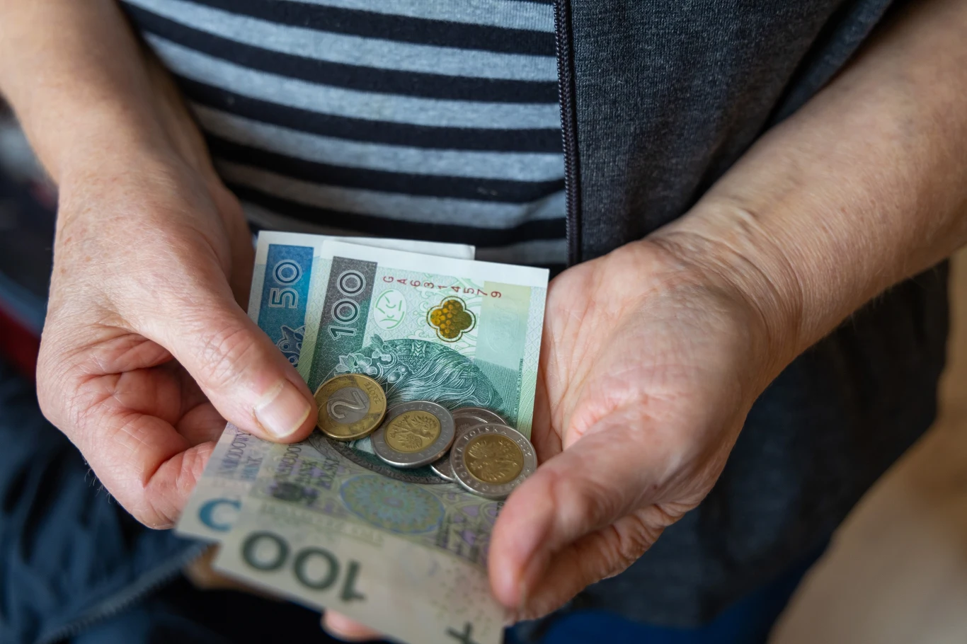 W 2026 roku wzrośnie płaca minimalna Kobieta trzyma w rękach pieniądze - banknoty i bilon