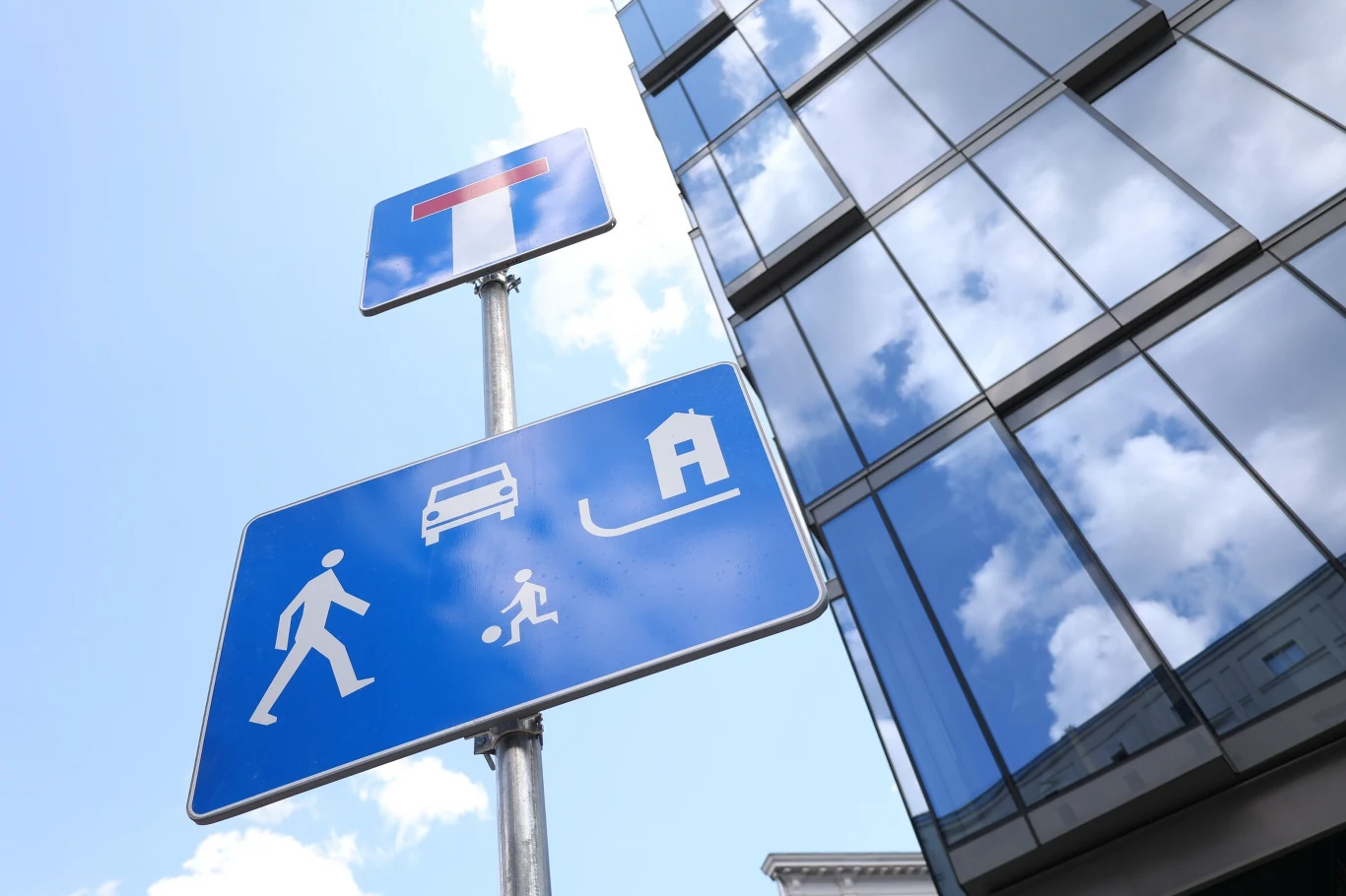 Niebieska tablica z symbolami domu, samochodu, dziecka z piłką i osoby dorosłej - znak D-40 wprowadza kierowców w strefę, gdzie zasady ruchu drastycznie się zmieniają. Niebieska tablica z symbolami domu, samochodu, dziecka z piłką i osoby dorosłej - znak D-40 wprowadza kierowców w strefę, gdzie zasady ruchu drastycznie się zmieniają.