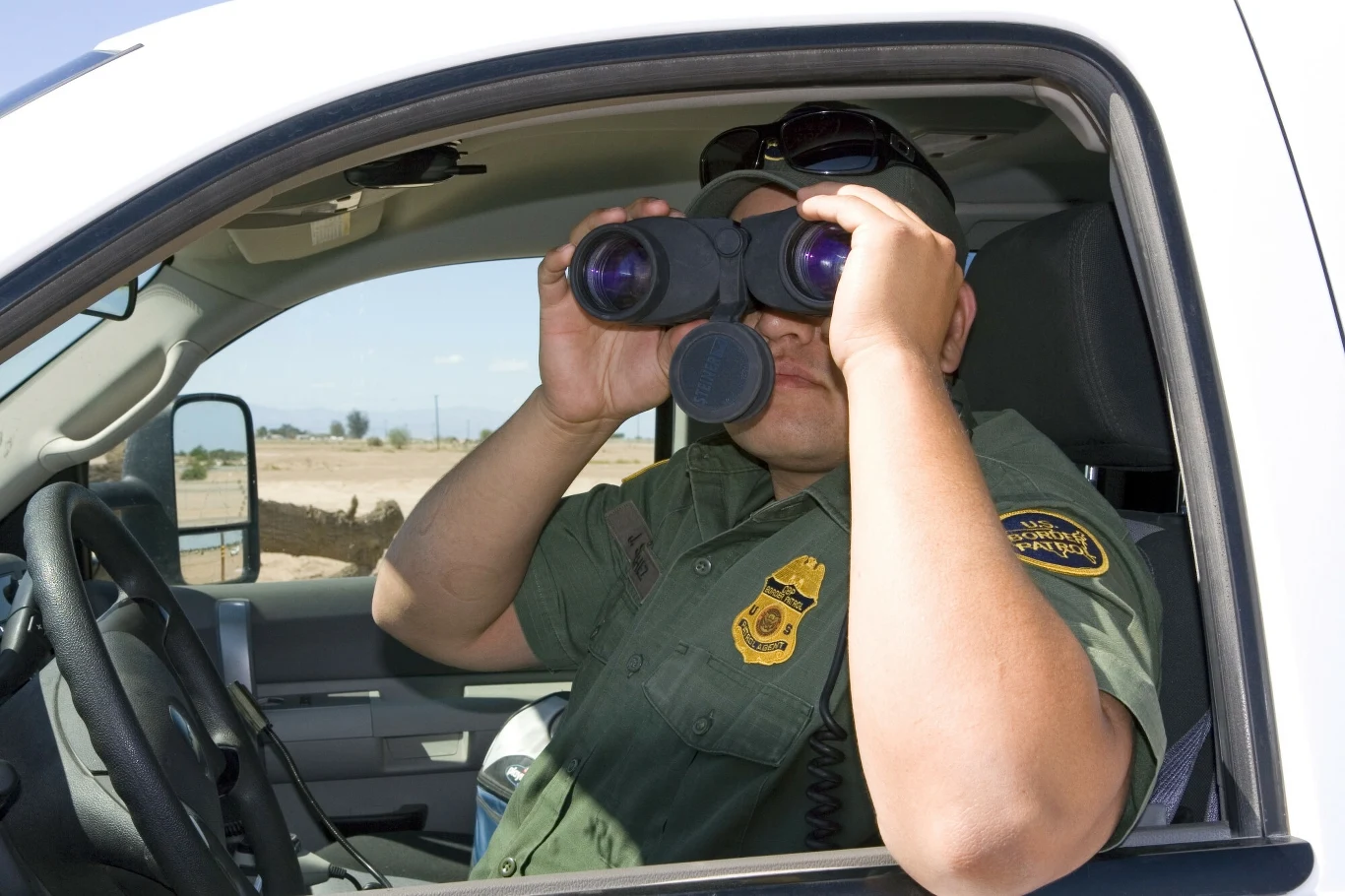 United States Border Patrol agent using binoculars to locate illegal immigrant crossings at the U.S./Mexico border along the All American Canal near Calexico, California. United States Border Patrol agent using binoculars to locate illegal immigrant crossings at the U.S./Mexico border along the All American Canal near Calexico, California.