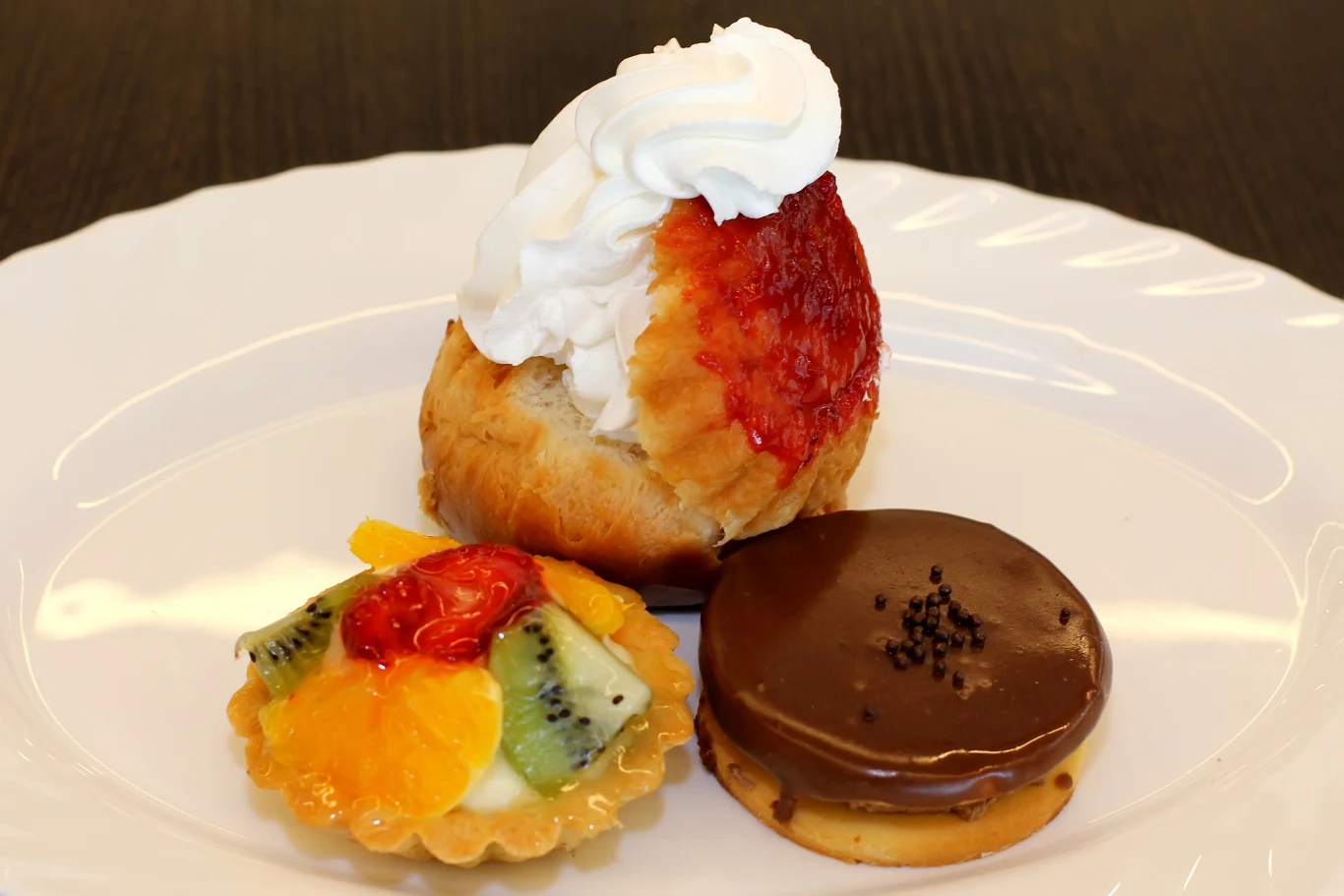 Babka Savarin z bitą śmietaną, obok tartaletka z francuskim kremem flan i Isler, czyli orzechowo -czekoladowe ciastko z morelowym nadzieniem