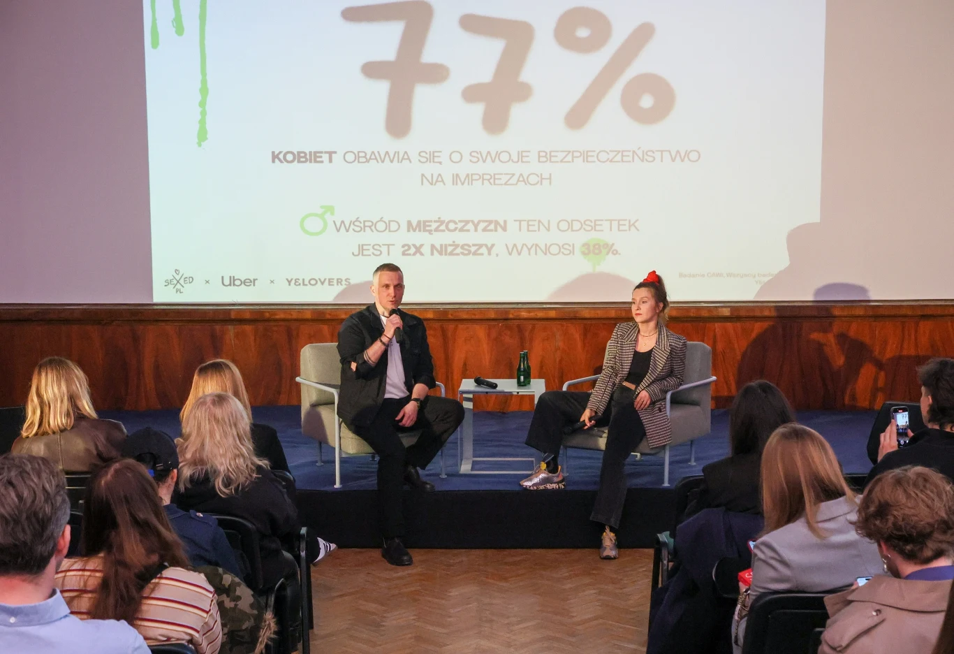 Kobieta i mężczyzna siedzą na scenie podczas konferencji prasowej