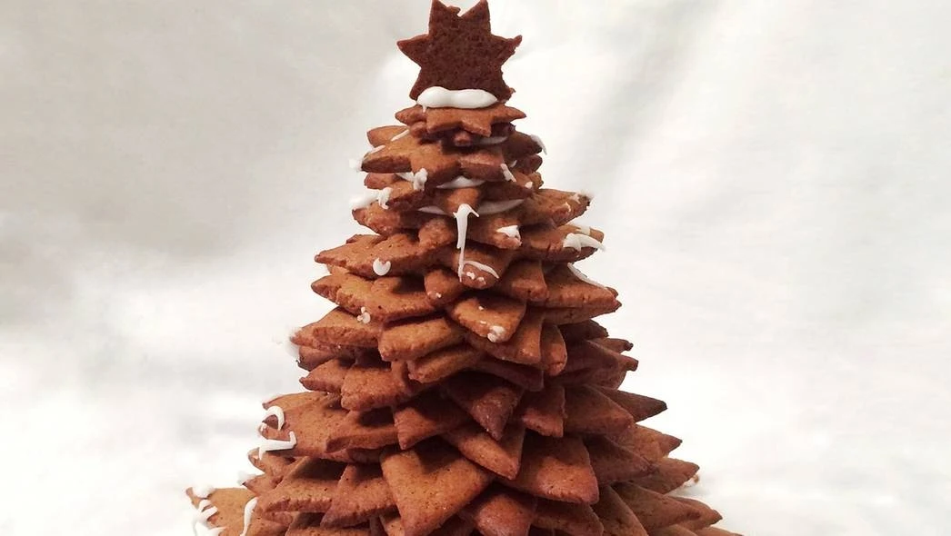 pixabay.com/ Ekologiskt_Skafferi Piernikowa choinka złożona z ułożonych na sobie warstw ciastek w kształcie gwiazdek, zwieńczona gwiazdką i ozdobiona lukrem.