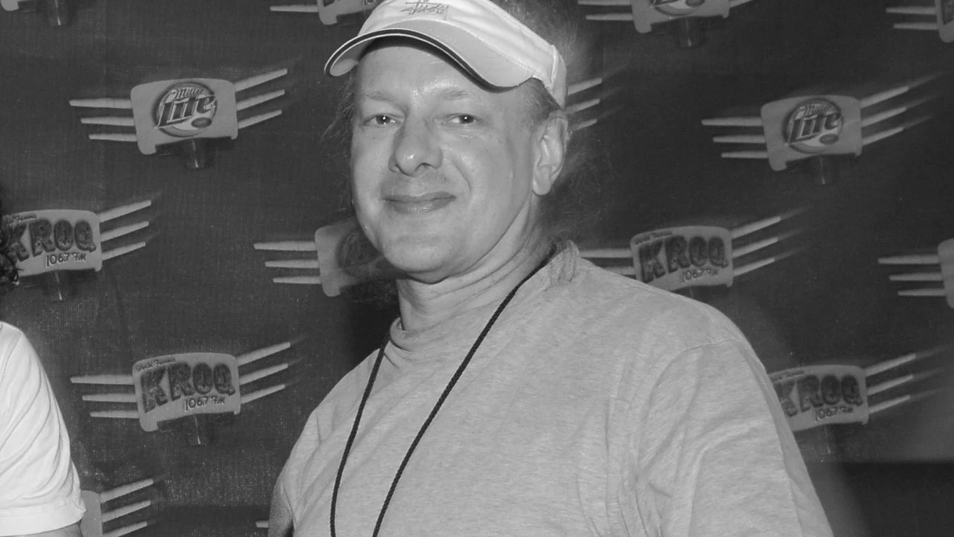 Nie żyje Jed Gould Mężczyzna w czapeczce z daszkiem pozuje na tle ściany z logo marki napoju. Ubrany w koszulkę, z zawieszonym identyfikatorem na szyi.