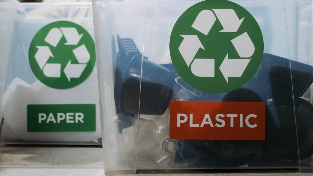 Pojemniki do recyklingu z wyraźnymi oznaczeniami: papier i plastik, z dużymi zielonymi symbolami recyklingu na etykietach.