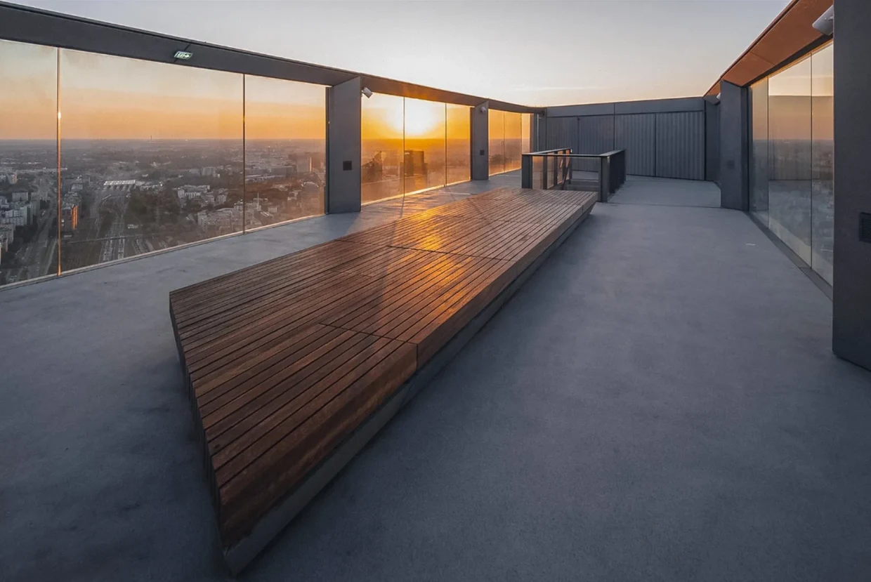 Widok z pewnością będzie zachwycał Taras widokowy z drewnianymi elementami konstrukcyjnymi, otoczony szklanymi balustradami z widokiem na miasto o zachodzie słońca.