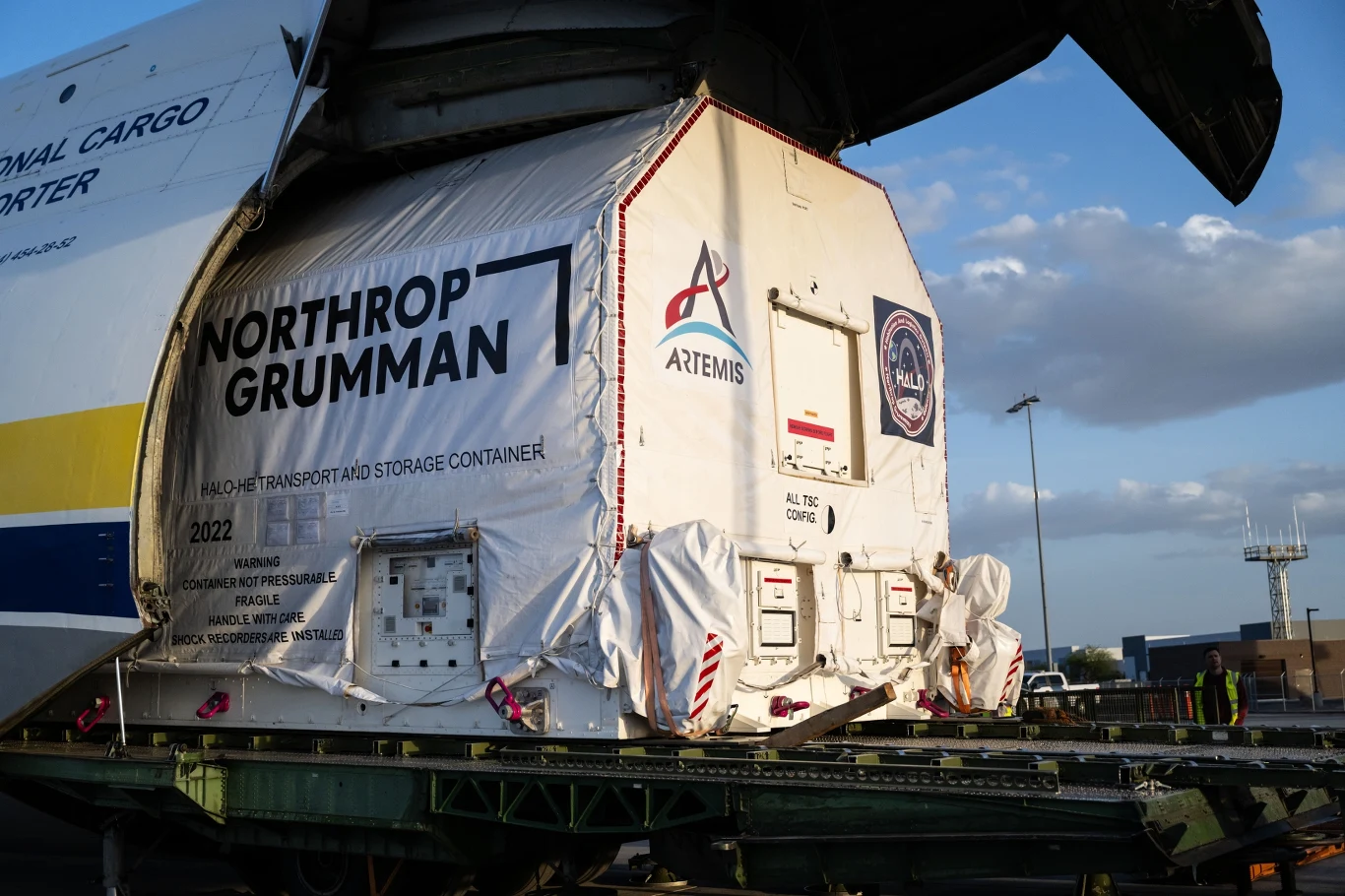 Kontener transportowy Northrop Grumman otwierany w trakcie załadunku na samolot, z widocznymi logotypami misji Artemis i oznaczeniami firmy, przystosowany do przechowywania wartościowych ładunków.