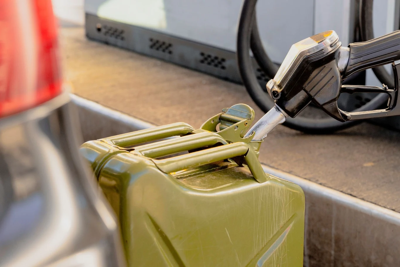 Tankujesz na zapas? Powinieneś znać kilka ważnych zasad. Zbliżenie na tankowanie paliwa do zielonego kanistra na stacji benzynowej, widoczny wąż dystrybutora.