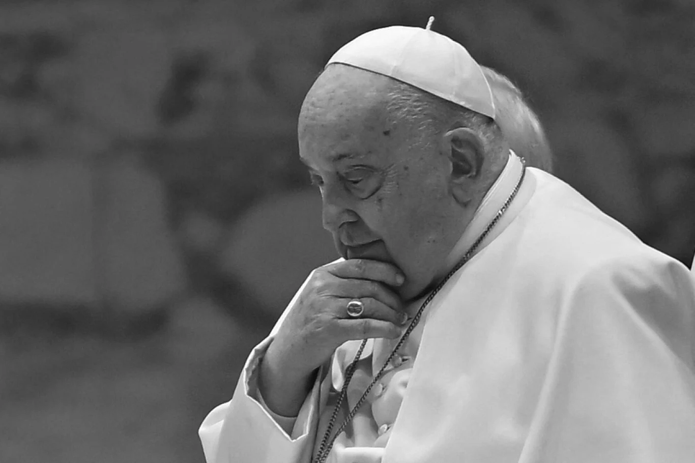 Papież Franciszek nie żyje. Tak wyglądały ostatnie godziny jego życia Mężczyzna w białej sutannie i piusce, zanurzony w zamyśleniu, wspierający brodę na dłoni, w tle rozmyty wzór.