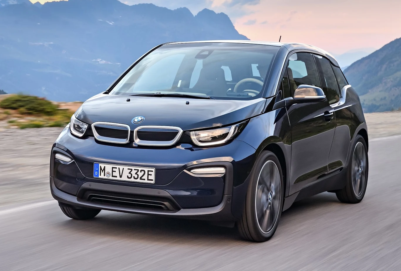 BMW i3 Nowoczesny samochód elektryczny BMW i3 o eleganckim, kompaktowym designie jadący po otwartej drodze, w tle górski krajobraz.