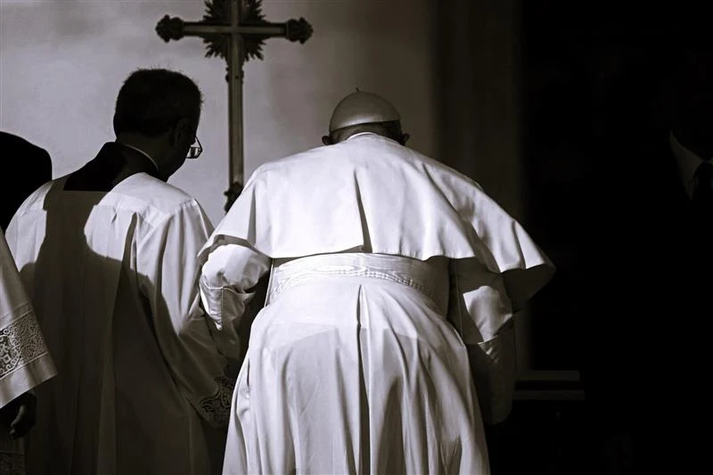 Ostatnie słowa papieża Franciszka. Wypowiedział je tuż przed śmiercią Duchowni w liturgicznych szatach, tylna perspektywa, krzyż w tle na ciemnym tle.