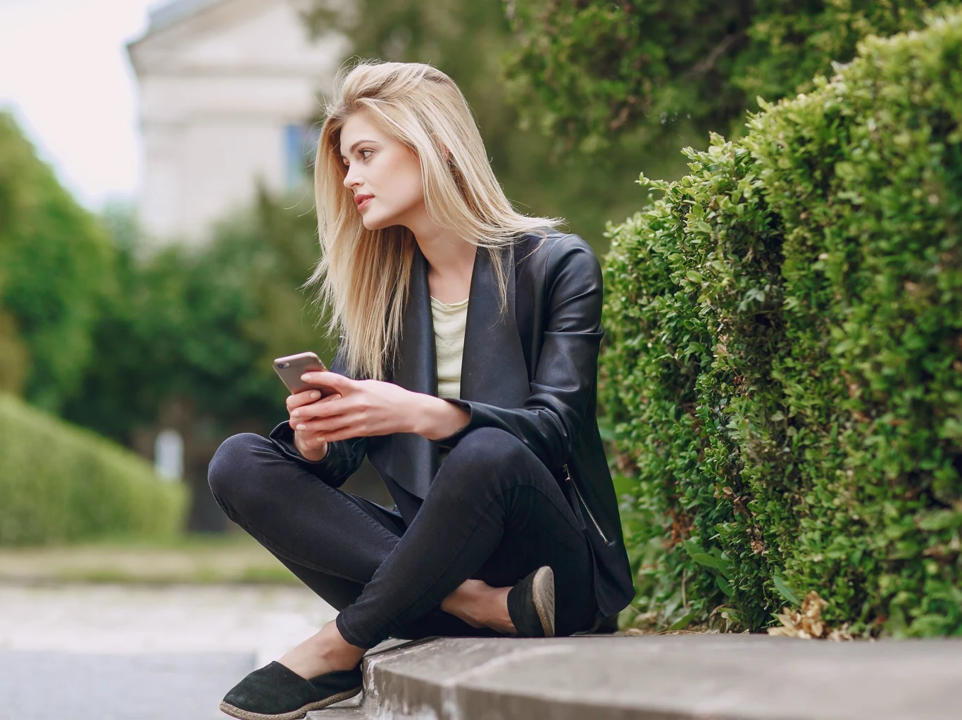 "Zetki" panicznie boją się odbierać połączenia przychodzące Młoda kobieta o blond włosach siedzi na zewnątrz na krawężniku z telefonem w dłoni.