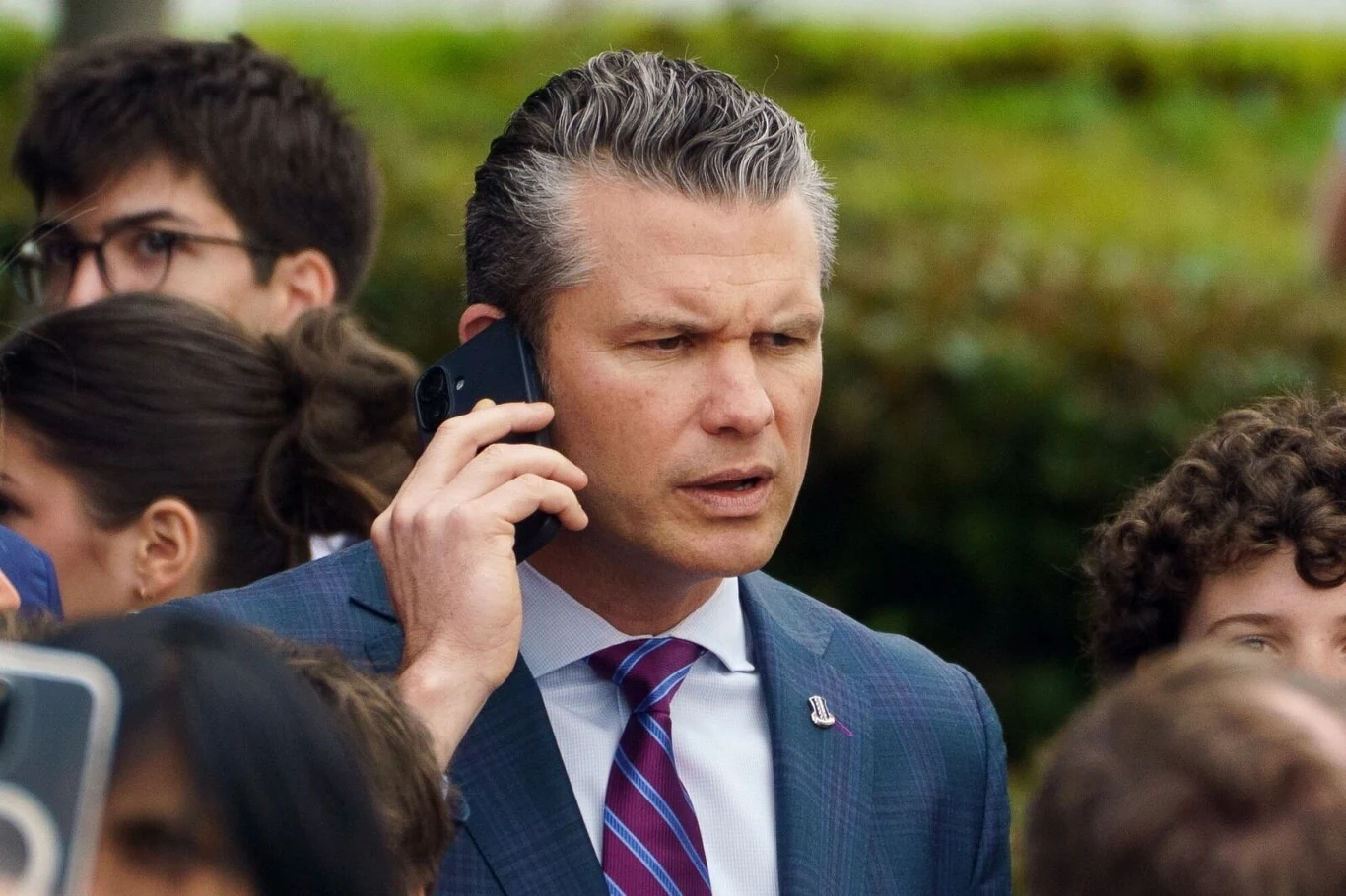 Alarmujące słowa szefa Pentagonu. Chodzi o bezpieczeństwo Europy Mężczyzna w garniturze rozmawia przez telefon komórkowy, otoczony przez grupę ludzi. Wygląda na zatroskanego lub skoncentrowanego, znajduje się na zewnątrz w otoczeniu zieleni.