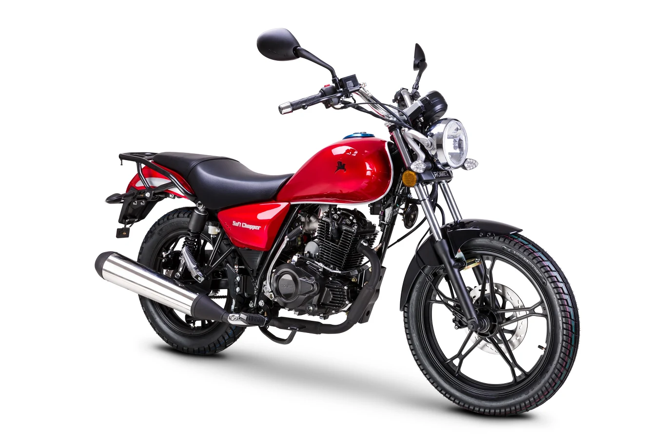 Czerwony motocykl o klasycznym designie z okrągłym reflektorem i czarną kierownicą, widoczny z boku na białym tle. Duży, chromowany tłumik oraz wygodne siedzenie na dwie osoby. Koła wyposażone w opony o głębokim bieżniku.