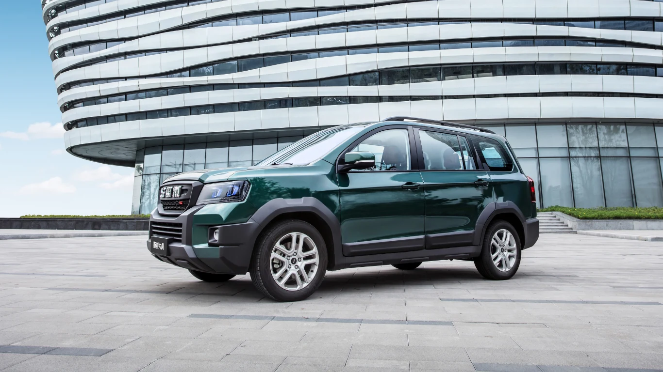 SWM G03F Zielony SUV o nowoczesnym wyglądzie stoi na tle futurystycznego budynku.