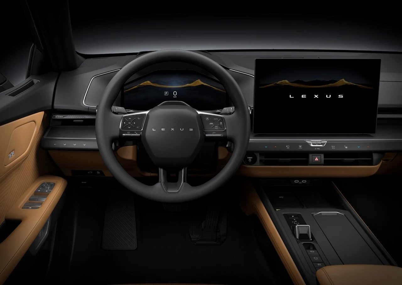 Wnętrze samochodu Lexus z widocznym eleganckim kokpitem. Centralnym elementem jest kierownica z logo marki, obok wyświetlacz pokazujący nazwę 'Lexus'. Starannie zaprojektowane wnętrze, skórzane wykończenia w odcieniach brązu.