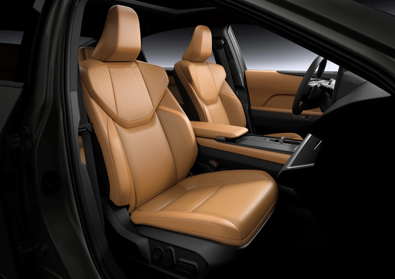 Luksusowe wnętrze samochodu z jasnobrązowymi, skórzanymi fotelami przednimi oraz nowoczesną konsolą środkową.